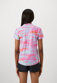Short-sleeved athletic shirt in pink, blue, and orange hues with a wavy pattern. Features a round neckline and a subtle logo at the back.