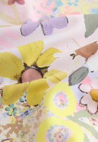 Květinová látka s žlutými, levandulovými a růžovými květy na světlém pastelovém pozadí, s hladkou texturou a živými vzory.