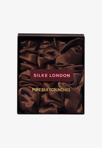 Brązowe jedwabne gumki do włosów zapakowane w czarne pudełko z przezroczystą pokrywką. Charakteryzują się gładką fakturą, subtelnym połyskiem i delikatnym, pomarszczonym wzorem.