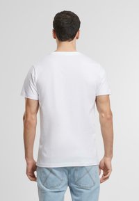 Hvit bomull T-skjorte med korte ermer og rund hals, med en glatt tekstur og enkelt design. Brukt med lyseblå denimjeans.