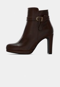 Σκούρο καφέ δερμάτινο μποτάκι μέσης με τακούνι και διακοσμητική αγκράφα σε λευκό φόντο.