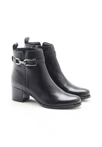 Botas de tobillo de cuero negro con tacones bajos en bloque, cremalleras en los laterales y detalles de hebilla plateada en los lados exteriores.