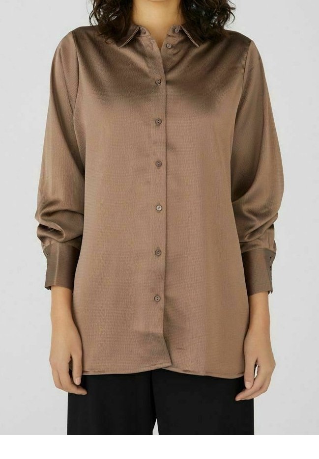 Blusa in satin marrone a maniche lunghe con bottoni e colletto, indossata con pantaloni neri, mostrata da metà petto ai fianchi.
