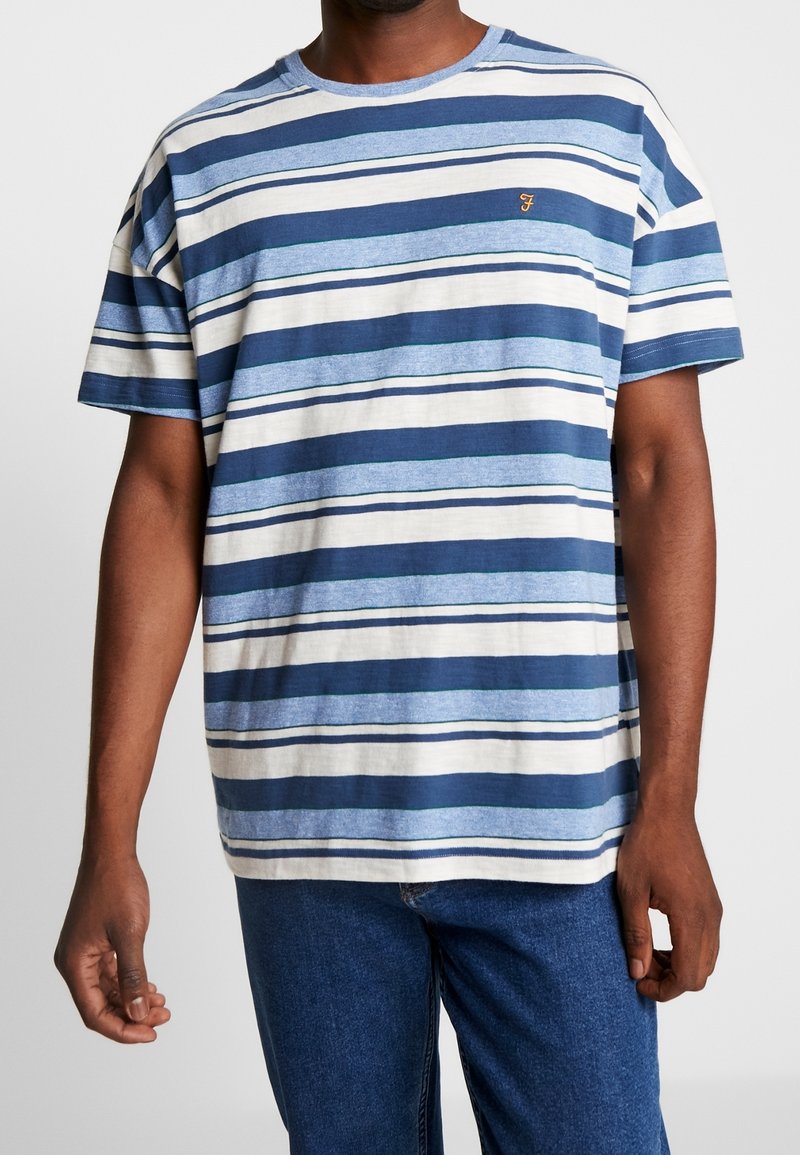 T-shirt à manches courtes rayé dans des tons de bleu et de crème, avec un col rond classique et un petit logo brodé sur la poitrine.