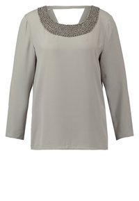 Lichtgrijze langemouwen top met een ronde halslijn en zilveren kralenaccenten. De stof lijkt soepel met een losse, casual pasvorm.