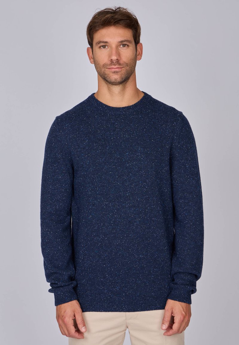 Pull en maille bleu marine avec un col rond, des manches longues et une texture finie avec des éclats de bleu plus clair.
