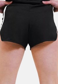 Schwarze Sportshorts mit weißen Seitstreifen, die einen hohen Schnitt und einen glatten Stoff aufweisen, wodurch das minimalistische Design des Kleidungsstücks betont wird.