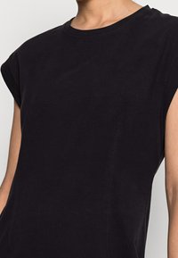 T-shirt sans manches noir en coton doux, avec un col rond et une coupe décontractée agrémentée de subtils détails de couture.