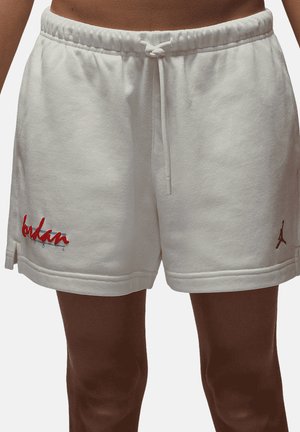 Pantaloncini bianchi con coulisse indossati da una persona, con testo rosso in corsivo e un piccolo logo nero vicino agli orli inferiori su ciascun lato.