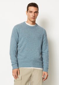 Hellsblauer Strickpullover mit rundem Halsausschnitt, gerippten Bündchen und Saum, der dezente mehrfarbige Sprenkel im gesamten Material aufweist.