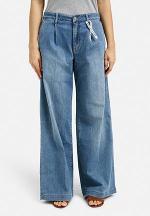 Helle blaue, weite Jeans mit hoher Taille, Vorderfalten und einem Etikett. Der Stoff scheint Denim mit einer glatten Textur zu sein.