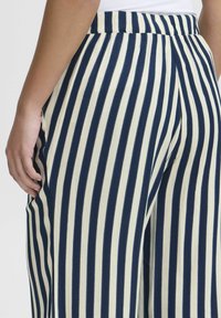 Navy and cream-striped pants with a relaxed fit. Features a soft fabric, wide leg design, and elastic waistband for comfort.