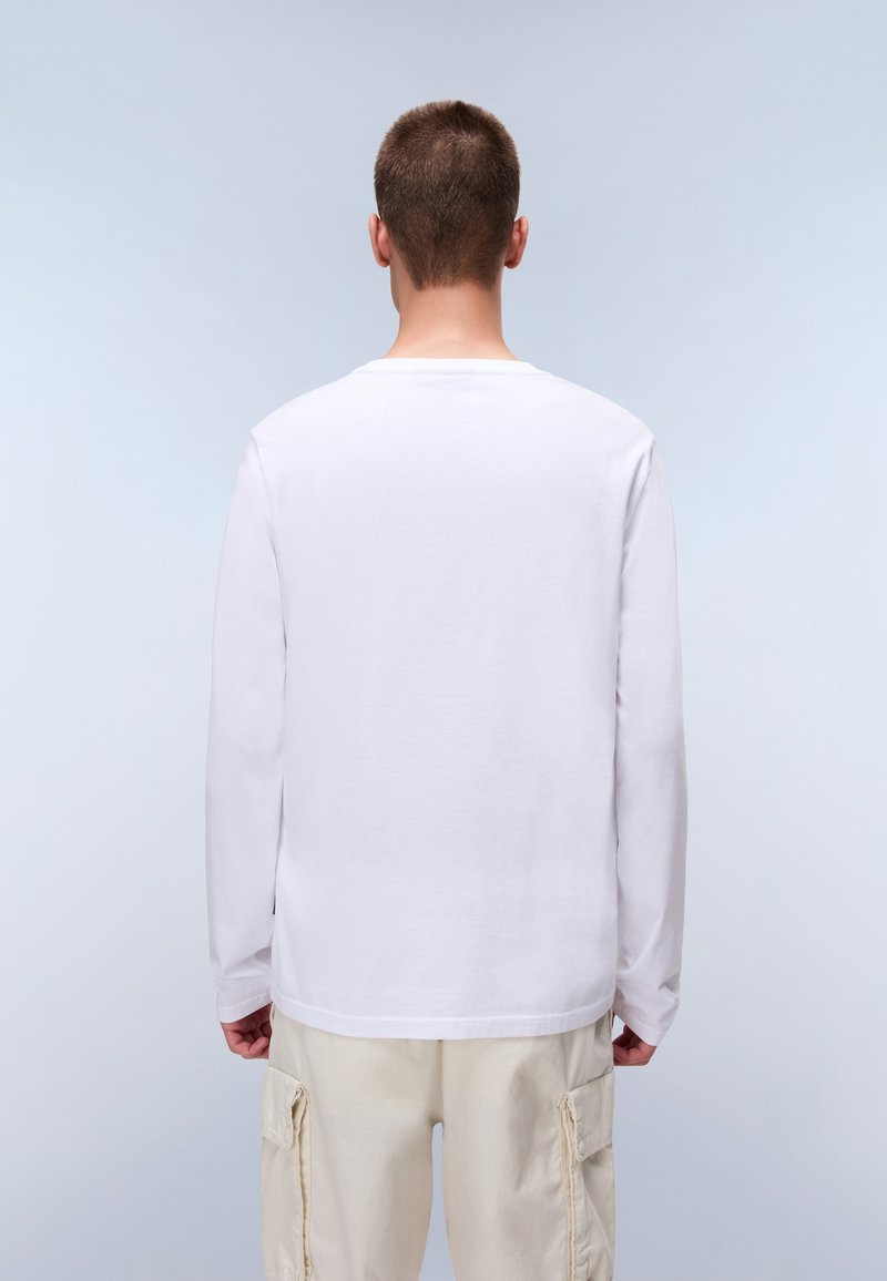 T-shirt bianco a maniche lunghe con collo rotondo, realizzato in cotone. Presenta una vestibilità comoda ed è abbinato a pantaloni cargo beige chiaro.