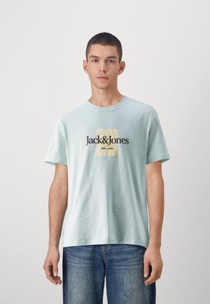T-shirt en coton bleu clair à manches courtes, col rond, avec impression de logo à l'avant en noir et jaune. Coupe décontractée avec une texture douce.