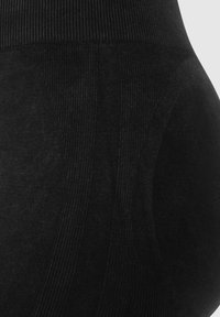 Schwarze, hochtaillierte Leggings mit strukturiertem, geripptem Bund, ausgestattet mit glatten Einsätzen und unregelmäßigen Nähten für ein figurschmeichelndes Design.