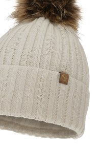 Bonnet blanc en tricot avec une texture côtelée, surmonté d'un pompon en fausse fourrure marron et d'une petite étiquette de marque marron sur le côté.
