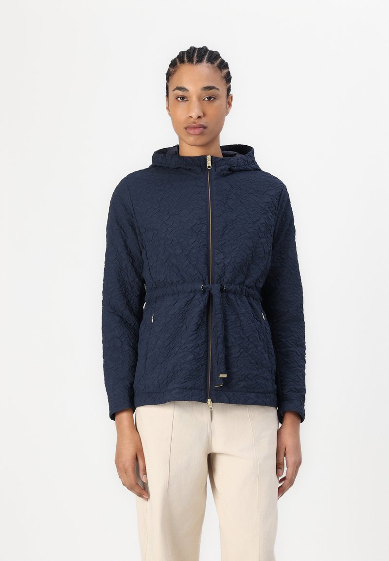 Ναυτικό μπουφάν με κουκούλα φτιαγμένο από υφασμένο ύφασμα, διαθέτει μπροστινό φερμουάρ, ρυθμιζόμενη μέση με κορδόνι και δύο πλευρικές τσέπες με χρυσές λεπτομέρειες.