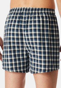 Miestne modro-biele kockované boxerky so elastickým pásom, vo voľnom strihu, vyrobené z ľahkej bavlny.
