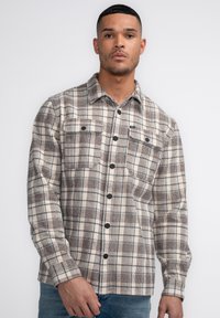 Braun- und cremefarbener kariert Flanellhemd mit zwei Brusttaschen und schwarzen Knöpfen, im lässigen Schnitt und mit langen Ärmeln.