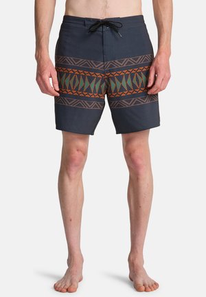 Herenzwembroek in donker marineblauw, met een geometrisch patroon in oranje en groen rond de taille. Gemaakt van lichtgewicht, sneldrogend materiaal.