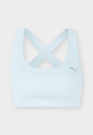 Lys blå sports-bh med brede kryssstropper og Puma-logo på venstre bryst, vist mot en ensfarget bakgrunn.