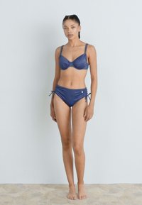Fato de banho de duas peças em tecido azul-escuro. Sutiã com aro e alças ajustáveis, combinado com parte de baixo de cintura alta com laços laterais.