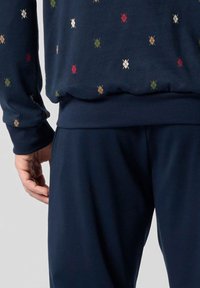 Felpa blu navy con finitura testurizzata, caratterizzata da un motivo a diamante in rosso, verde e beige. Maniche e vita con bordi a costine.