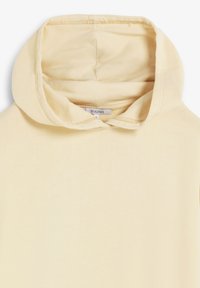 Gelber Baumwoll-Hoodie mit weicher Textur, einem geräumigen Kapuzen und einem schlichten Design. Enthält ein Etikett am Ausschnitt, das die Marke angibt.