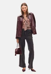 Burgundyröd lackjacka, leopardmönstrad blus med fluga, svarta högmidjade jeans med sidodetalj, burgundyröd handväska, spetsiga klackar.