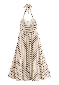 Abito a pois in tessuto beige, con pois neri, corpetto arricciato, spalline a halter e gonna svasata.