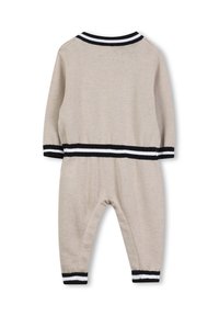 Beige gebreide jumpsuit met lange mouwen, voorzien van zwart-wit gestreepte ribboorden en tailleband. Zachte textuur, comfortabele pasvorm.
