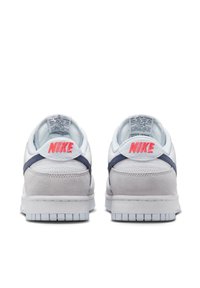 Vita och ljusgrå Nike-sneakers med mocka och meshmaterial, med en rosa logotyp och marinblå detaljer p å hälen.