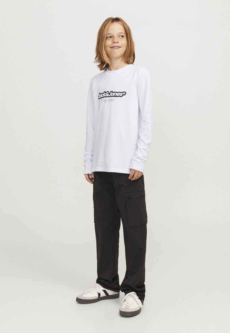 Biały t-shirt z długim rękawem z czarnym logo "Jack & Jones", zestawiony z czarnymi spodniami cargo z bocznymi kieszeniami i gładką teksturą, noszony z trampkami.