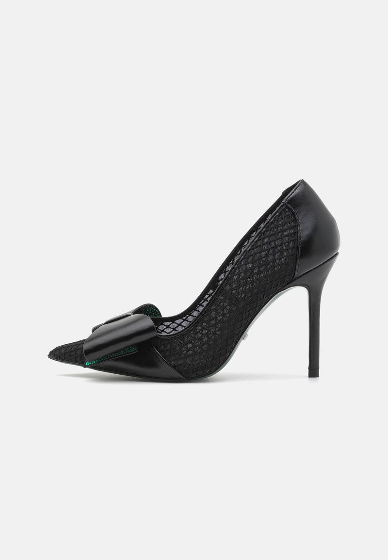 Black high-heeled shoe with a pointed toe, featuring a smooth leather front and textured mesh sides, adorned with a large bow detail.