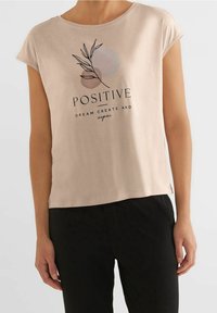 Svetle růžové tričko s krátkým rukávem vyrobené z měkké bavlny s grafickým textem "POZITIVNÍ" a designem listu; volný střih, rovný lem.