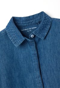 Camicia di denim con colletto blu, caratterizzata da leggeri pois blu chiaro, stile classico con bottoni e morbido al tatto. L'etichetta riporta "Republic of Denim."