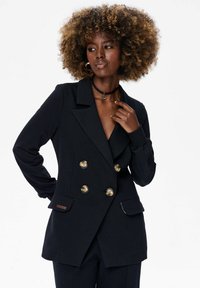 Zwarte dubbelgemonteerde blazer met gouden knopen, notch-kraag, zijzakken en een gladde textuur. Heeft aansluitende mouwen en een slank ontwerp.