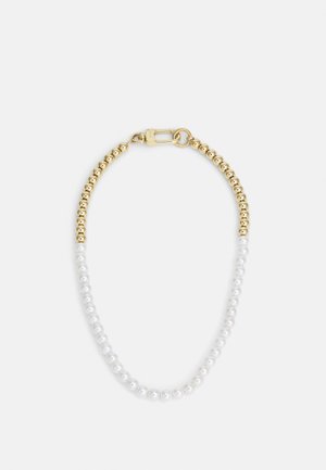 Collier avec moitié perles dorées et moitié perles blanches, avec un fermoir en or sur fond blanc.