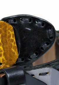 Schwarzer Lederoberschuh mit matter Oberfläche, gelbem strukturiertem Akzent sowie gestickten und perforierten Details.