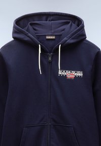 Felpa con zip blu navy realizzata in tessuto morbido, con un logo frontale che presenta un design di bandiera, coulisse e due tasche anteriori.