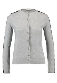 Grå cardigan med rund halsringning, långa ärmar, femknappslåsning och svarta fransar längs axlarna. Mjuk stickad textur.