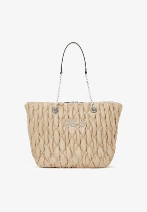 Beige kviltota rokassoma, kas izgatavota no mīkstas ādas, ar sudraba ķēdes rokturi, apakšā ar rāvējslēdzēju un izceltu zīmolu uz priekšu.