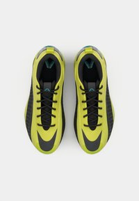 Scarpe atletiche verde lime e nere con superficie testurizzata, lacci piatti e accenti laterali prominenti. Presentano una suola imbottita e un collare imbottito.