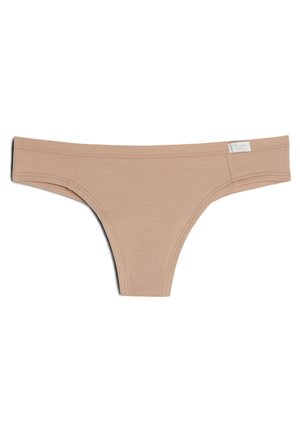 Nude-colored thong with a smooth texture, featuring minimal stitching and a tag on the right side. Simple, streamlined design.