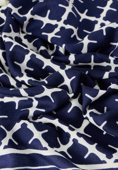 Ναυτικό ύφασμα με λευκό αφηρημένο σχέδιο, διαθέτοντας ομαλή υφή και ρευστό πέπλωμα. Το σχέδιο έχει καμπύλα σχήματα και ποικιλία μεγεθών σε όλη την επιφάνεια.