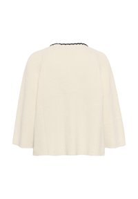 Stickad krämfärgad pullover med en kokongform, med en svart mönstrad halsringning. Tyget verkar mjukt och texturerat.