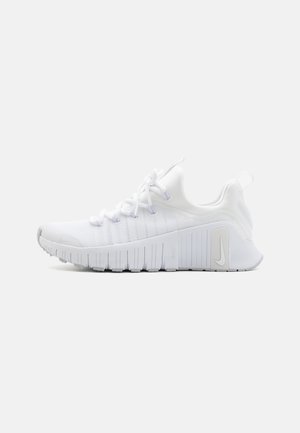 Hvid atletiksneaker med tyk, segmenteret sål, snørefront, trækstropper på tunge og hæl samt subtil Nike-logo på siden.