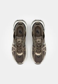 Nike Sneaker mit braunem Mesh-Obermaterial und gepolstertem Kragen, ausgestattet mit einer weißen Mittelsohle und dunklen Akzenten; inklusive Schnürsenkeln und markentypischem Logo.