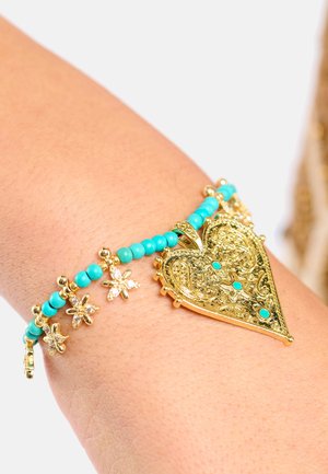 Bracelet en forme de cœur en or avec des perles turquoise et des accents floraux. Détails complexes sur le cœur, avec une texture lisse.