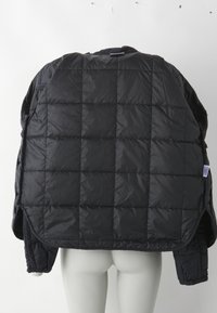 Doudoune noire avec un design matelassé, présentant une texture lisse et brillante ainsi que des poches latérales. Le col est haut et légèrement surdimensionné.